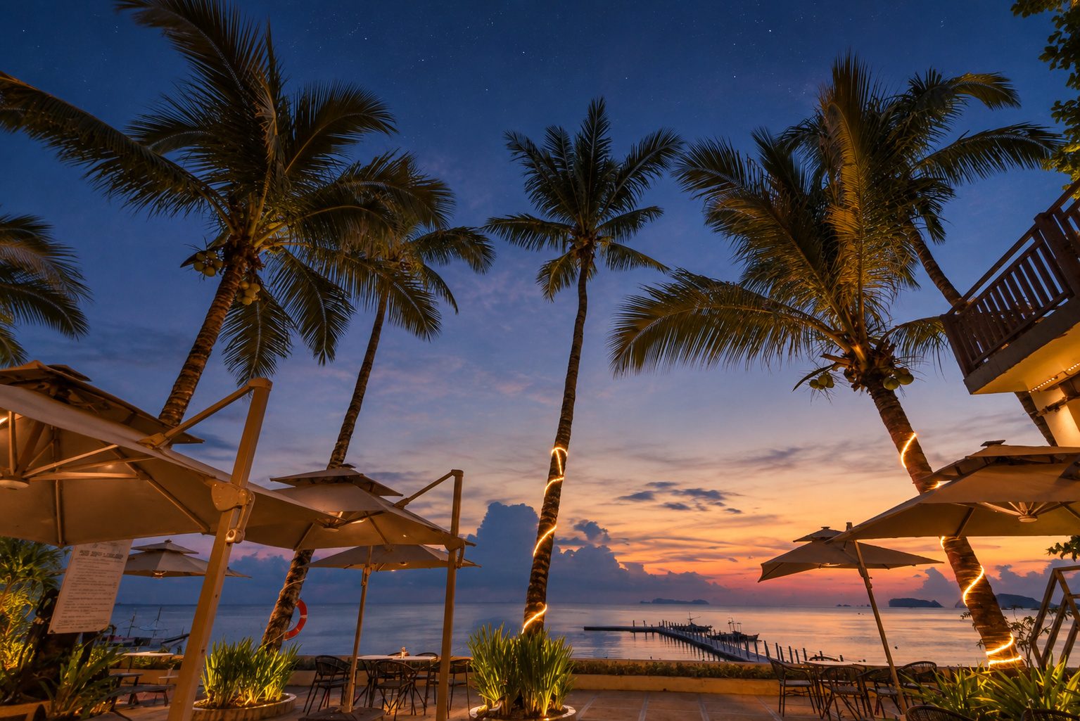 Palms and parasols on the beachfront at twilight
